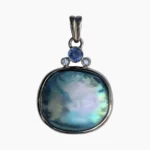 Pendant with a rare natural cushion-shaped abalone pearl measuring 19 x 17mm from Mendocino, California set in 14-karat yellow gold. Framed at the top with a 0.20-carat 3.5mm round Ceylon Sapphire and two 2.2mm round VS1G 0.04-carat diamonds.
