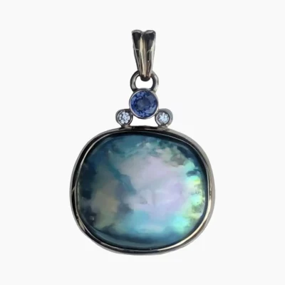 Pendant with a rare natural cushion-shaped abalone pearl measuring 19 x 17mm from Mendocino, California set in 14-karat yellow gold. Framed at the top with a 0.20-carat 3.5mm round Ceylon Sapphire and two 2.2mm round VS1G 0.04-carat diamonds.