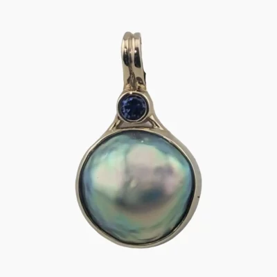 Pendant with a natural abalone pearl from Mendocino, California measuring 14 mm set in 14-karat yellow gold, accented with a 0.14-carat 3mm round Ceylon sapphire at the top.