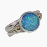 Ring featuring a round 1.46-carat opal from Coober Pedy, Australia measuring 10mm set in sterling silver with solid 14-karat yellow gold accents.