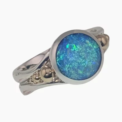 Ring featuring a round 1.46-carat opal from Coober Pedy, Australia measuring 10mm set in sterling silver with solid 14-karat yellow gold accents.