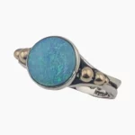 Ring featuring a round 1.56-carat opal from Coober Pedy, Australia measuring 10mm set in sterling silver with solid 14-karat yellow gold accents.