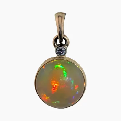 Pendant with a 2.62-carat round Ethiopian opal measuring 10mm set in solid 14-karat yellow gold with a 2mm round VS1G 0.03-carat accent diamond set in a 14-karat white gold bezel. Featuring a hinged bail.