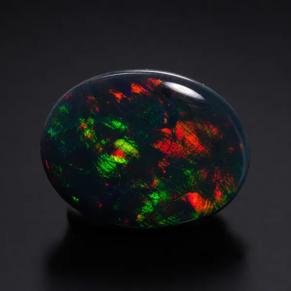 Loose black opal cabochon with a near-black body and bright red and green play of color