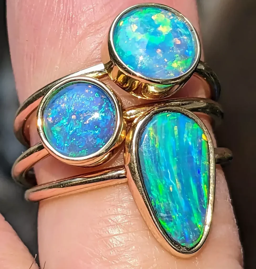 Three opal rings in gold worn stacked on a finger