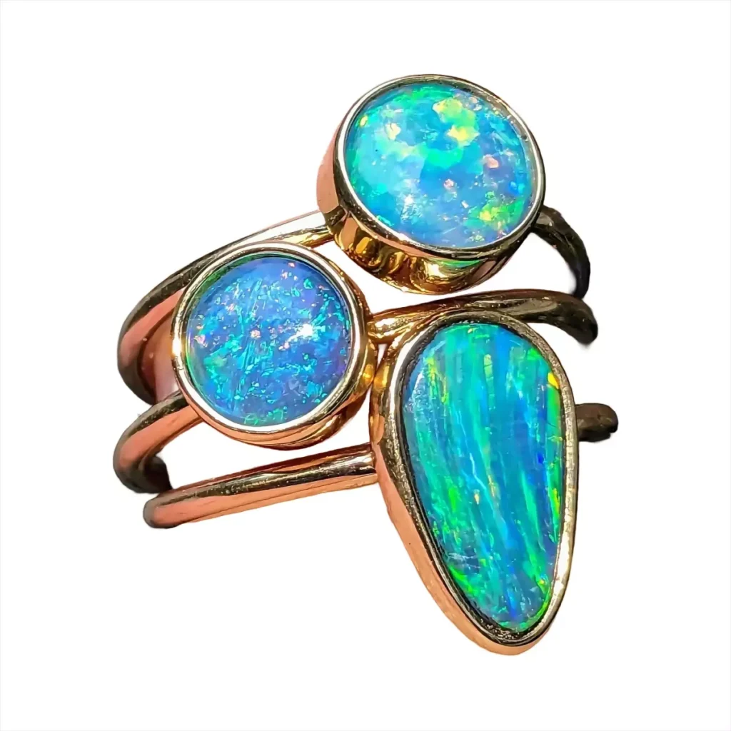 Three stacked gold rings with bezel-set blue and green opals
